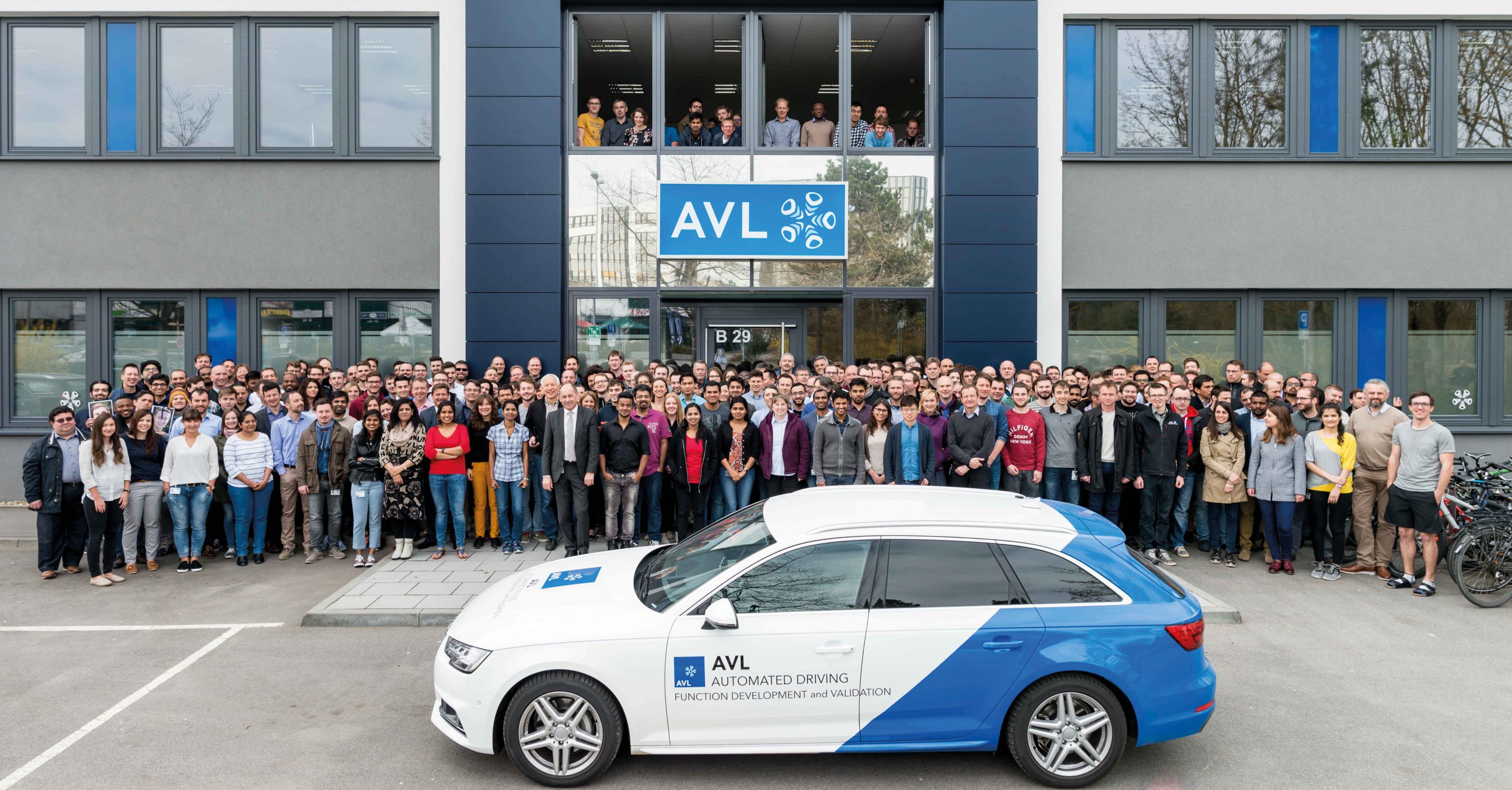 Mitarbeiter und AVL Auto vor Haupteingang in Regensburg