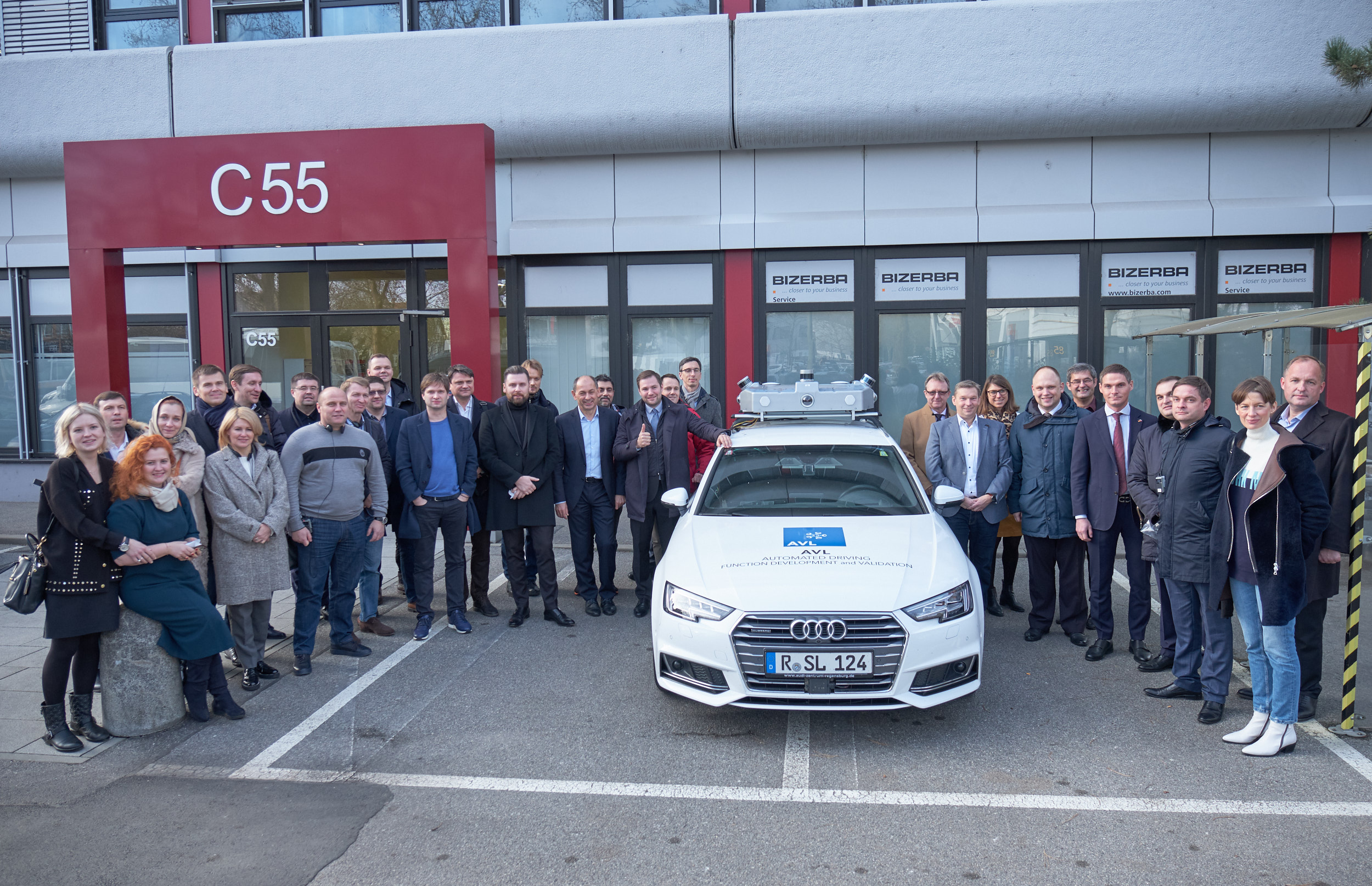AVL Software & Functions Mitarbeitende mit dem E-Coupé vor dem Bürogebäude in Regensburg